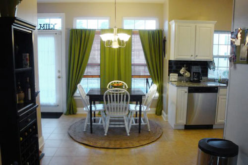 kitchen breakfast nook with rich green curtains on two windows