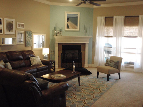 living room with corner fireplace and accent blue wall and white sheer curtains on dark rod