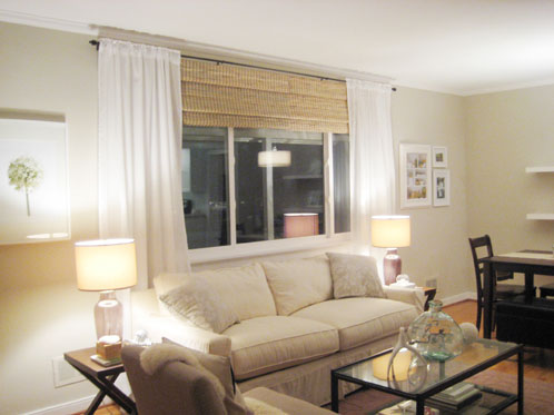 living room with white sheer curtains hung on oil rubbed bronze curtain rod with bamboo roman shades