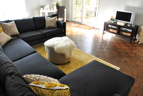 dark charcoal gray ikea sectional sofa in living room with yellow accents