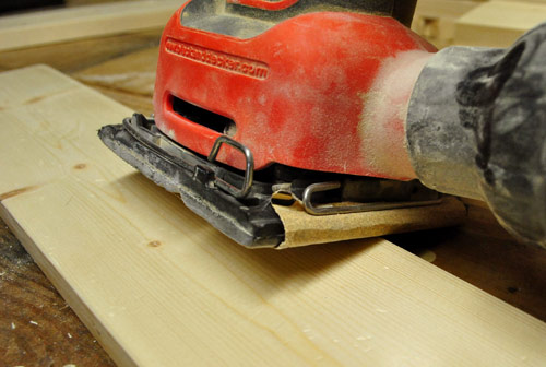 using a black & decker palm sander to smooth edges of wood board