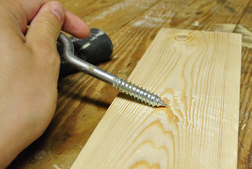 scraping course screw across new wood board to create distressed effect for DIY project