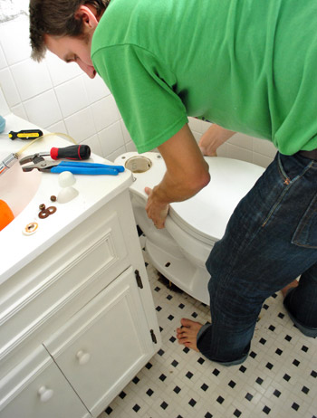 John placing toilet bowl back on floor over new wax ring