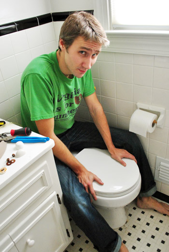 John applying pressure to toilet bow to secure wax ring in place