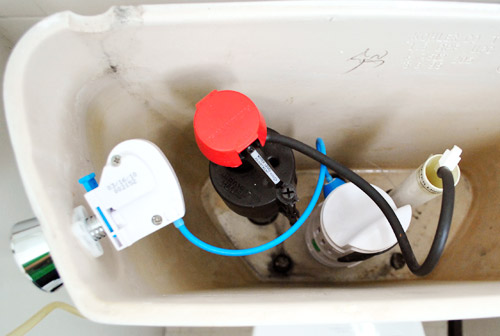 Dual flush toilet retrofit kit shown inside open toilet tank