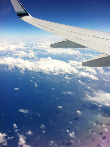 airplane wing over ocean with clouds