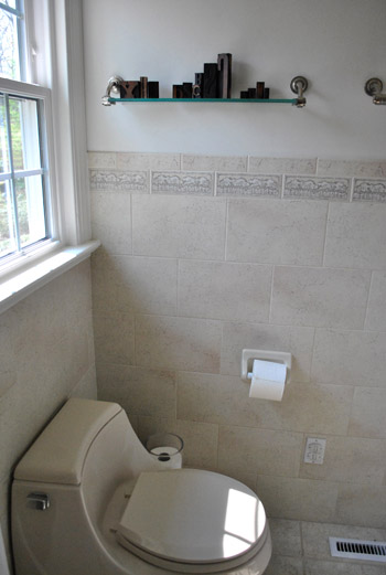 View Of Tile Wall In Dated Bathroom With Glass Shelf Over Toilet
