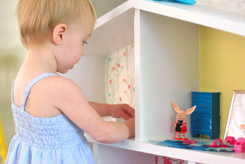 Close Up of Little Girl Playing With Olivia Pig Figurines In Homemade Dollhouse