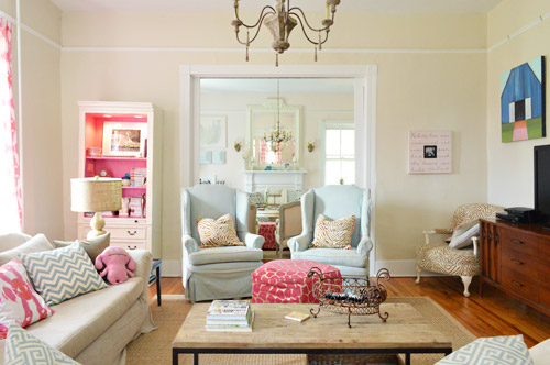 Colorful Traditional Farmhouse Living Room With Wingback Chairs And Pink Bookcase