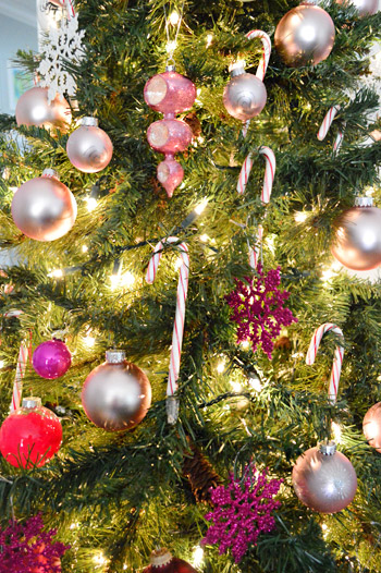 Close UP de enfeites rosa e vermelho e bengalas doces em uma árvore de Natal gradiente