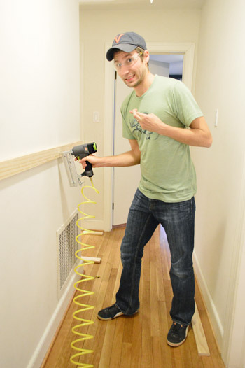 DIYer using Craftmans nail gun to install wood to wall, crossing fingers because its his first time using