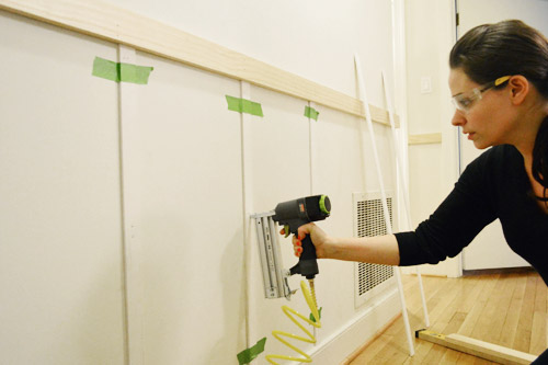 wearing safety goggles and using Craftmans nail gun to install vertical lattice strips to create battens in board and batten DIY project