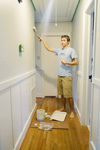 pintando um corredor cinza com um rolo de pintura usando Benjamin Moore Nature Paint na cor Moonshine