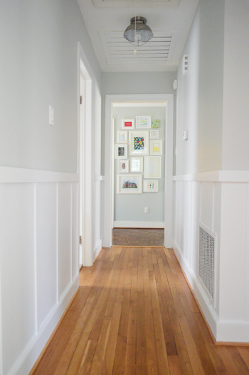 gray hallway with white board and batten trim molding looking at picture frame gallery