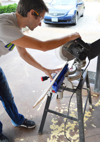 John using miter saw to make cut on crown molding