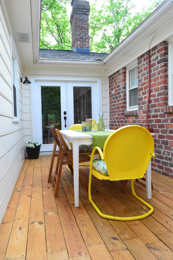 After Of Deck In Weird Alley Between Brick Ranch and Addition With Yellow Metal Vintage Chairs