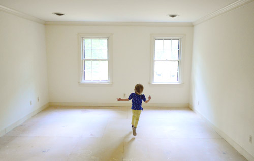 little girl running in empty room with no carpet