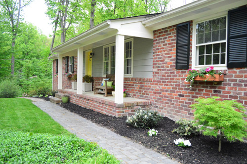 After Photo of Brick Ranch Front Porch With Yellow Door Black Shutters And Grassy Yard