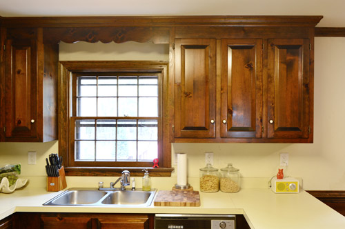 before photo of dated 1980s kitchen with dark wood wall cabinets