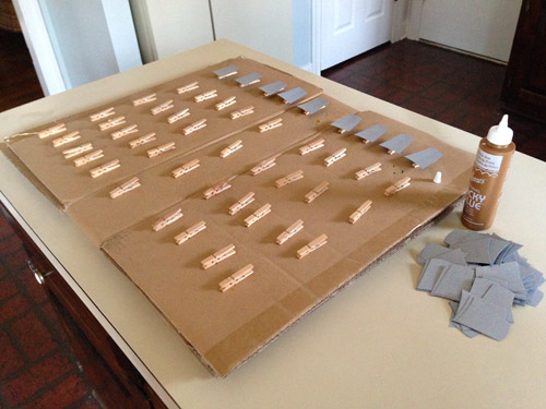 Glueing gray paper light socket cut outs onto clothespin for Christmas craft garland