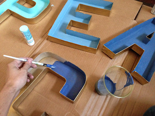 Painting inside of cardboard craft letter with blue gradient paint