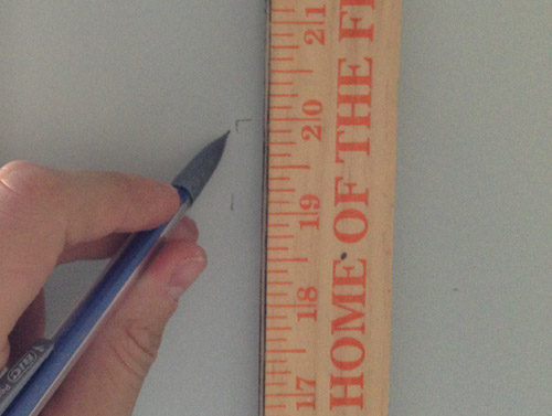 using a yardstick and pencil to mark the height and placement of kitchen floating shelves