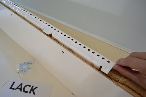 close-up detail of white metal hanging bracket for LACK Ikea floating shelf