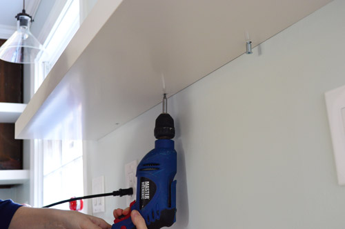 using powerdrill to screw Ikea floating shelf to secure it to wall bracket