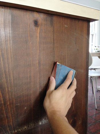 Lightly sanding wood cabinets before applying darker stain