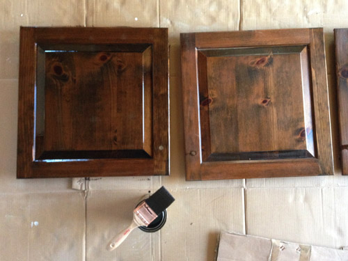 Cabinet doors laid flat on cardboard while being stained.