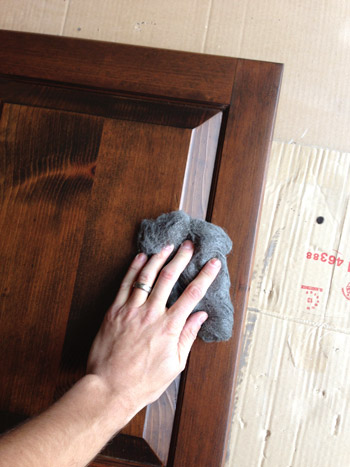 Sanding dark stained cabinet door front with extra fine steel wool