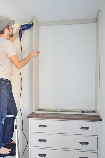 Man screwing into the side of a homemade DIY bookshelf