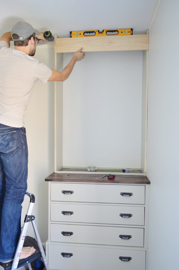 Man adding trim piece at the top of custom bookshelf