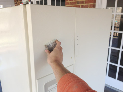 sanding fridge in preparation for paint