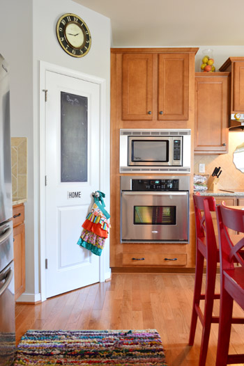 Kitchen With Wood Cabinets And Corner Pantry With Chalkboard Door