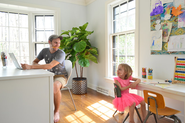 John and Daughter Working At Side By Side Desks In Home Office