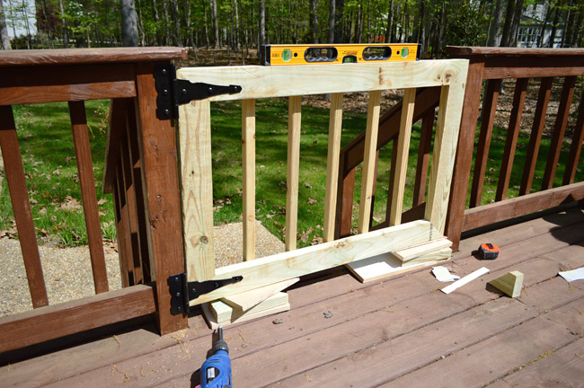 Deck Gate Installed Across Opening In Deck Railing Stairs using Level and Scrap Wood To Hold Into Place