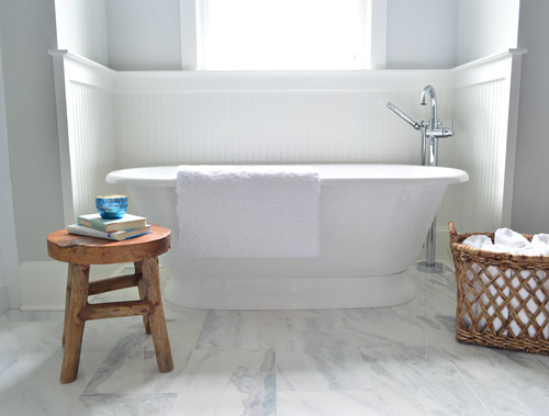 Wood Stool And Towel Basket Next To Freestanding Tub In Modern Bathroom