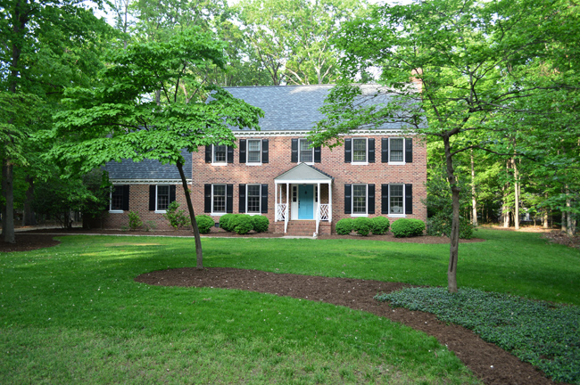 Front View Of Brick Colonial Home This Summer With Green Grass and Mulch Beds
