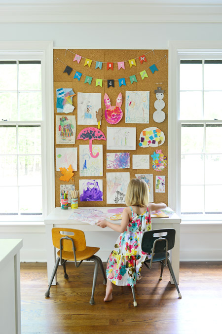 arte infantil exibida em um grande quadro de cortiça na parede do escritório em casa, acima da mesa de arte infantil