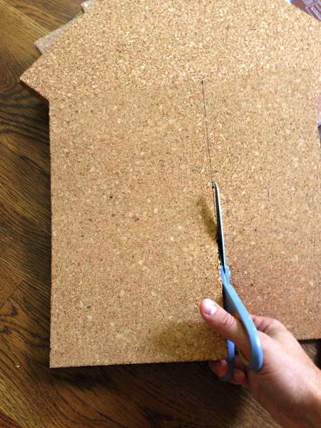 using scissors to cut cork tiles to fit to size on cork board wall