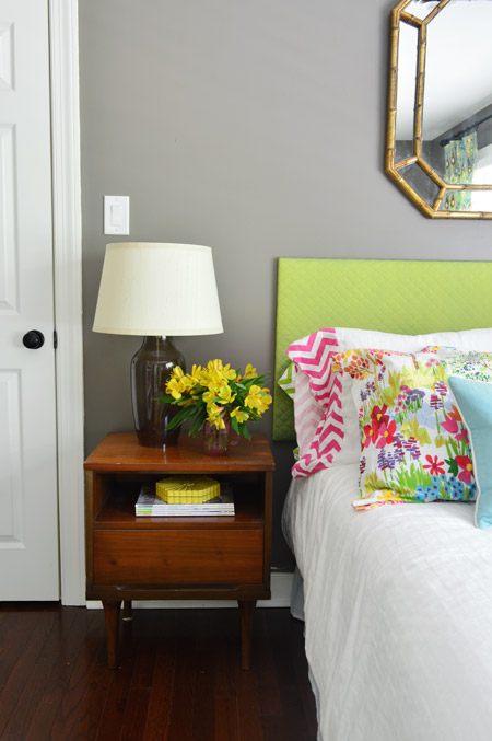 Side table in bedroom with colorful flowers and headboard