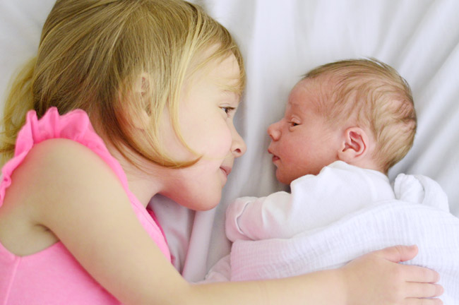 Big Sister And Baby Brother Side-By-Side In Bed