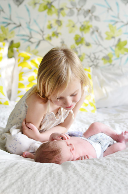 Big Sister Looking At Infant Baby Brother At DIY Newborn Photo Shoot