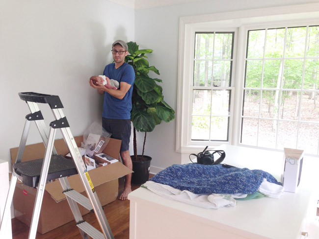 John Holding Infant Son On Arm In DIY Newborn Photo Shoot