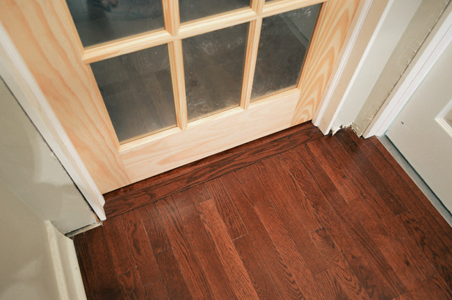 View Of Flooring Under Two Doors With Hardwood Threshold And Tile