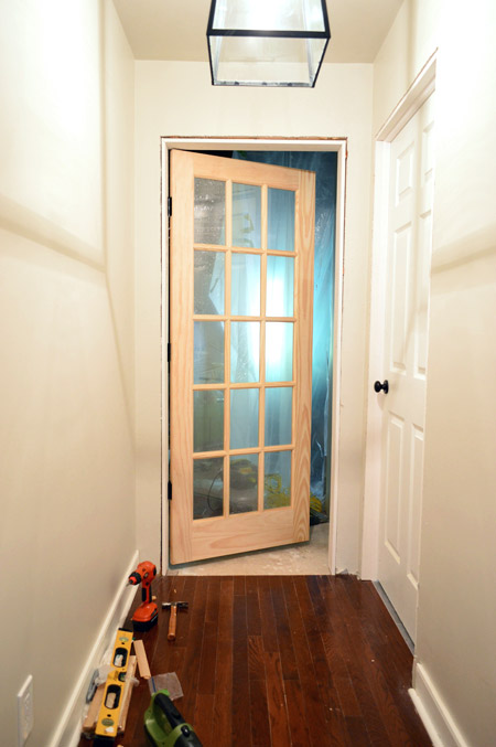 15 Pane Glass Unfinished Wood Door Hung At Entrance To Bonus Room In DIY Door Jamb