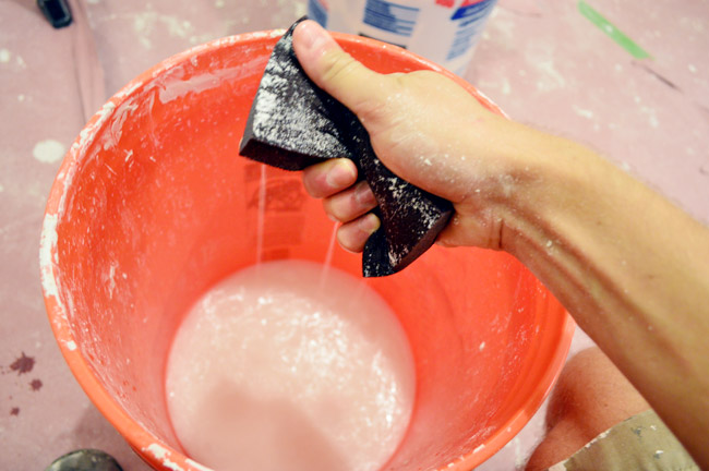 squeezing water out of sanding block like a sponge into a bucket