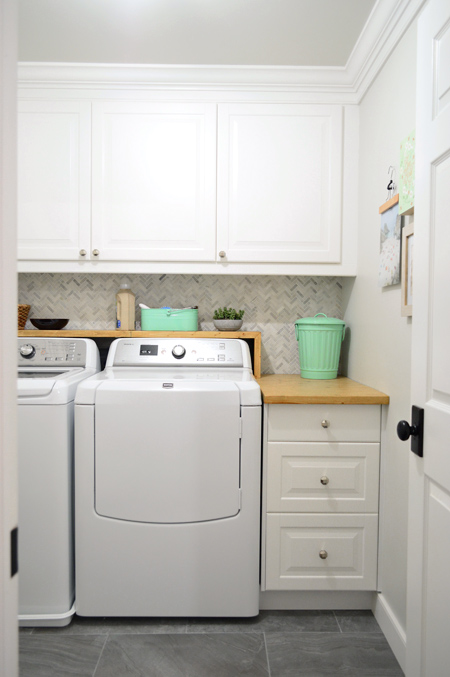 New Laundry Room With Ikea Cabinets And Wood Counter And Marble Herringbone Backsplash